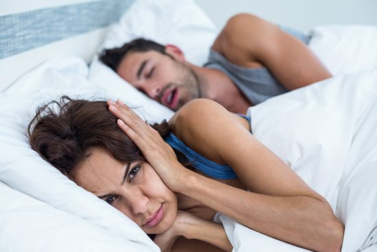 "Snoring man. Couple in bed, man snoring and xwoman can not sleep, covering ears with pillow for snore noise. Young interracial couple, Asian woman, Caucasian man sleeping in bed at home. Click on the banners for more of the same:"