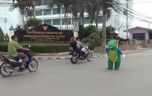 ตำรวจสวมชุดมาสคอตไดโนเสาร์ยืนโบกรถ