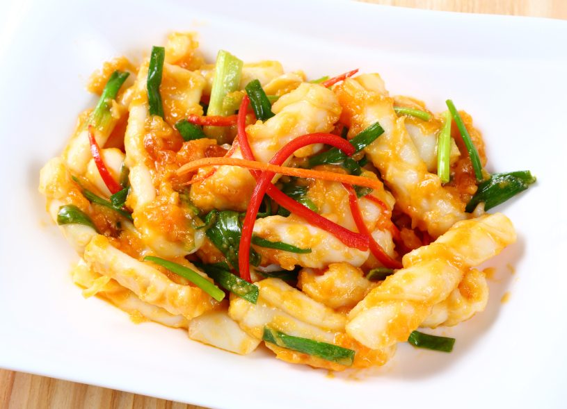 Close up stir fried squid with salted egg yolk on white dish